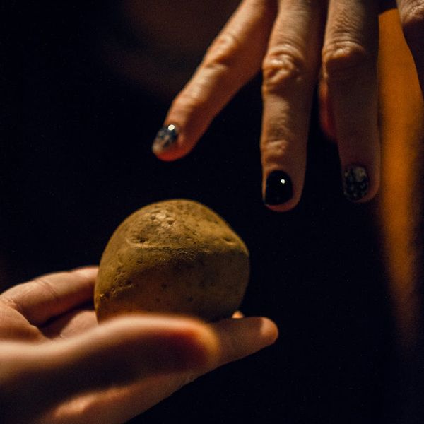 Close-up of hands in a meditative gesture against a dark background.